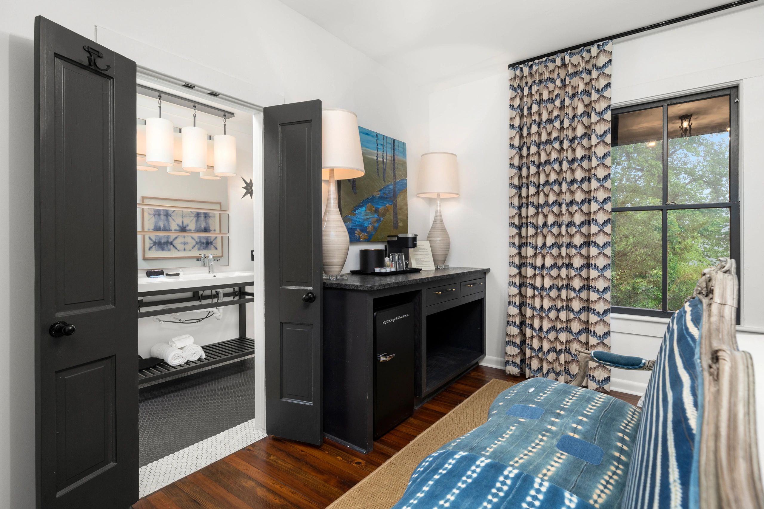Cozy bedroom with patterned curtains and open doors to a stylish bathroom